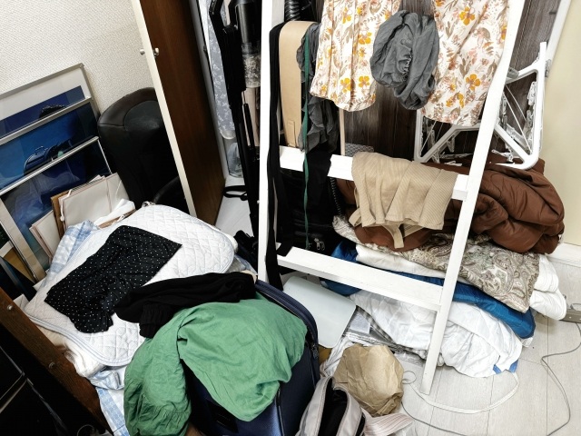 部屋に散らばる衣類と収納棚