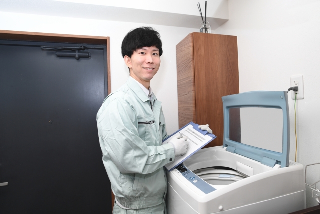 洗濯機を操作する作業服の男性